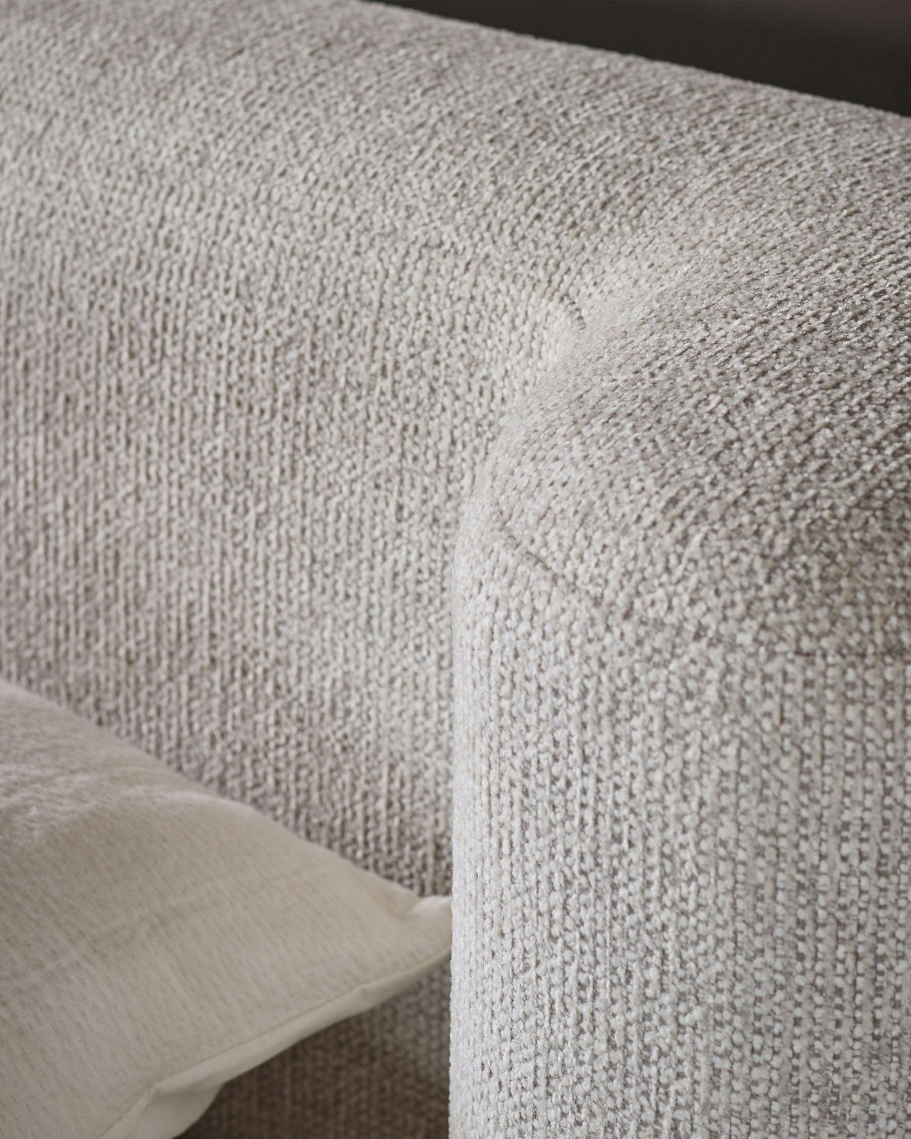 Close-up of natural beige textured fabric on Darla king-size ottoman bed, showing woven upholstery detail and corner seam.