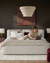 Darla King Size Ottoman Bed in natural fabric, styled in a contemporary bedroom with pendant lighting and warm wood accents.