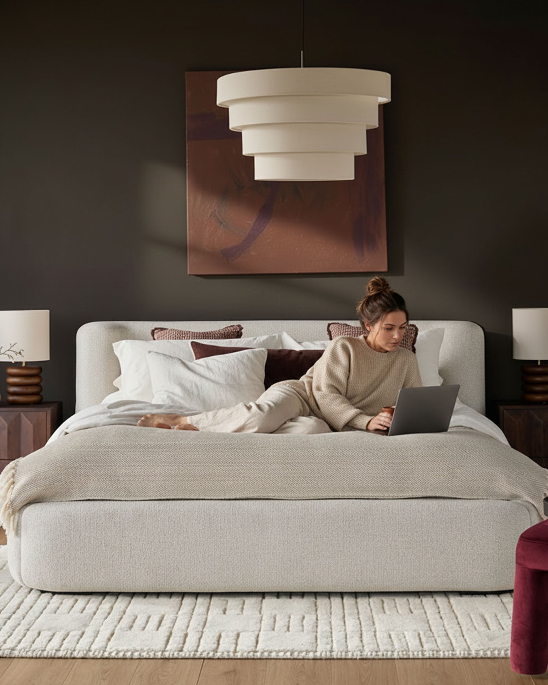 Darla King Size Ottoman Bed in natural fabric, styled in a contemporary bedroom with pendant lighting and warm wood accents.