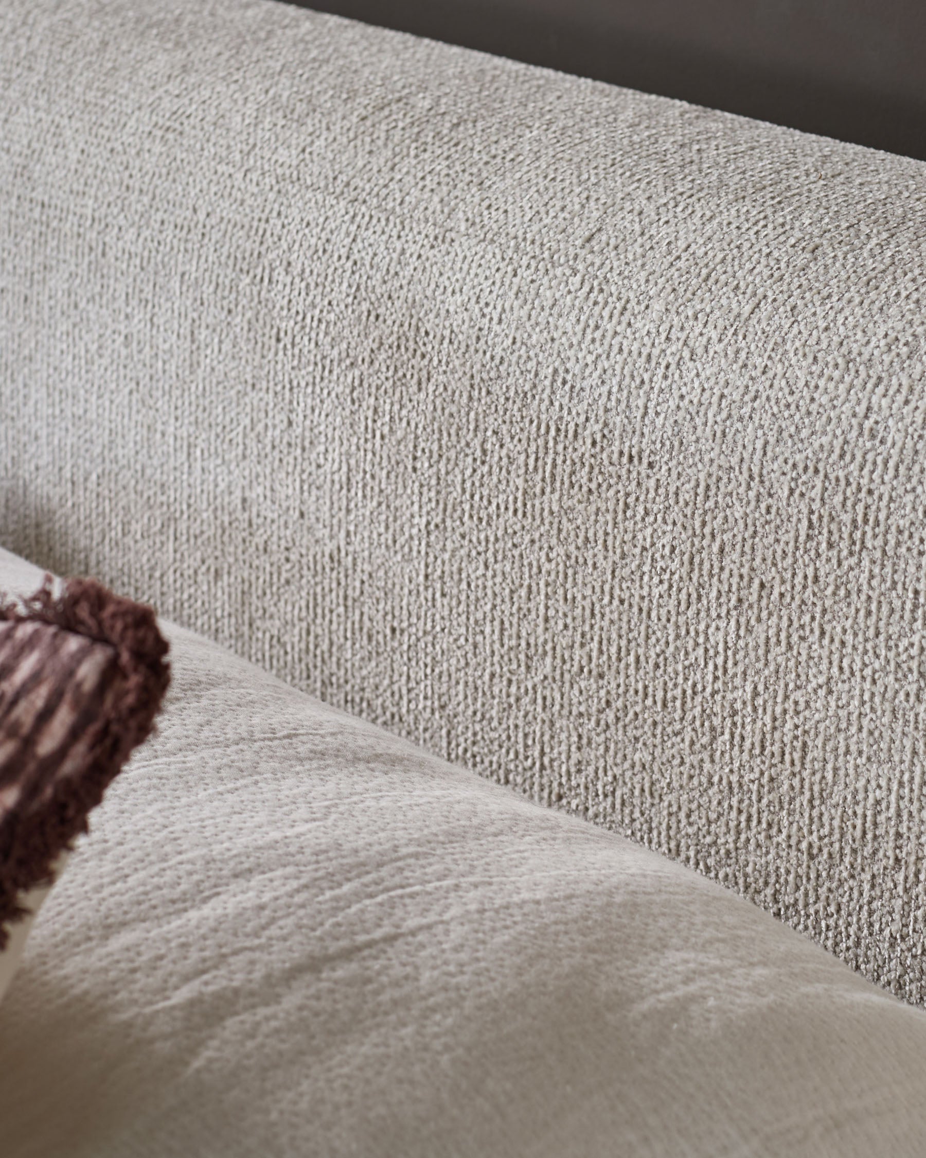 Close-up of natural beige fabric texture on Darla king-size ottoman bed with burgundy piping detail