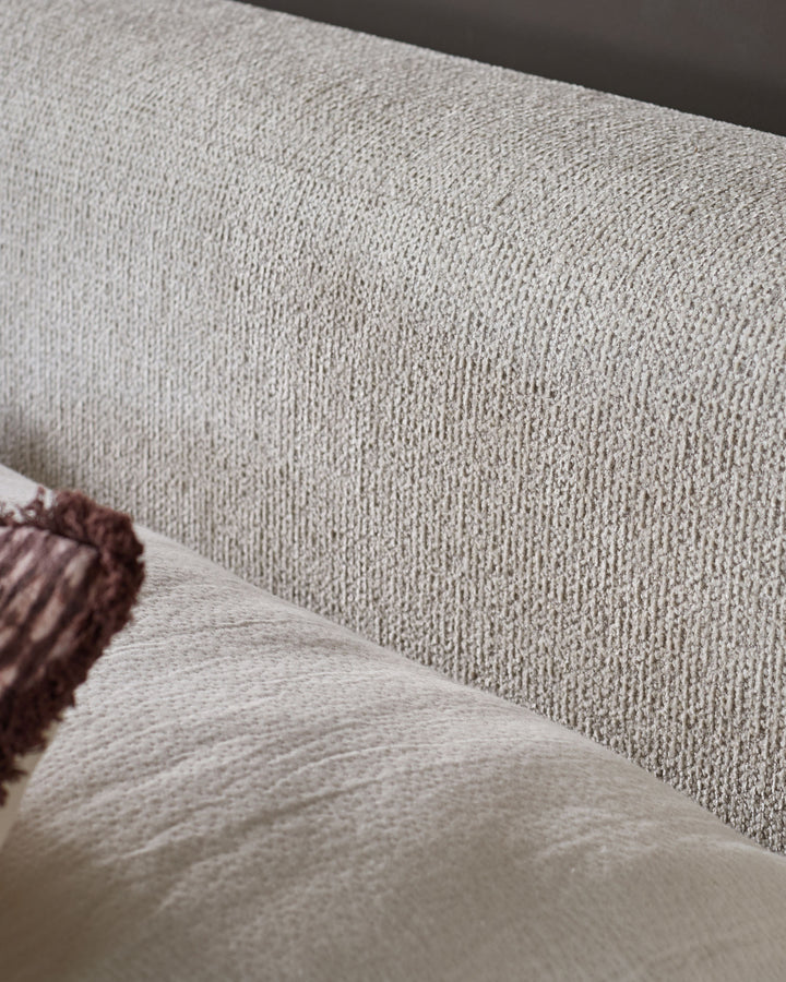 Close-up of natural beige fabric texture on Darla king-size ottoman bed with burgundy piping detail