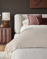 Darla king-size ottoman bed in natural fabric with rounded headboard, styled with cream bedding and burgundy accent pillows.