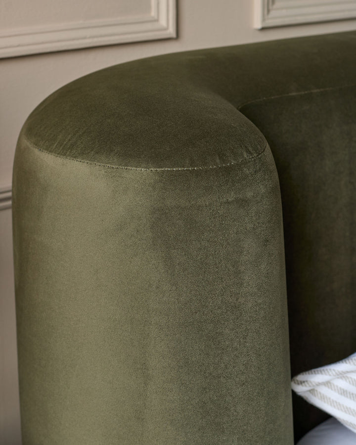 Darla King-Size Ottoman Bed in olive green velvet, close-up of rounded headboard with stitched seam detail.