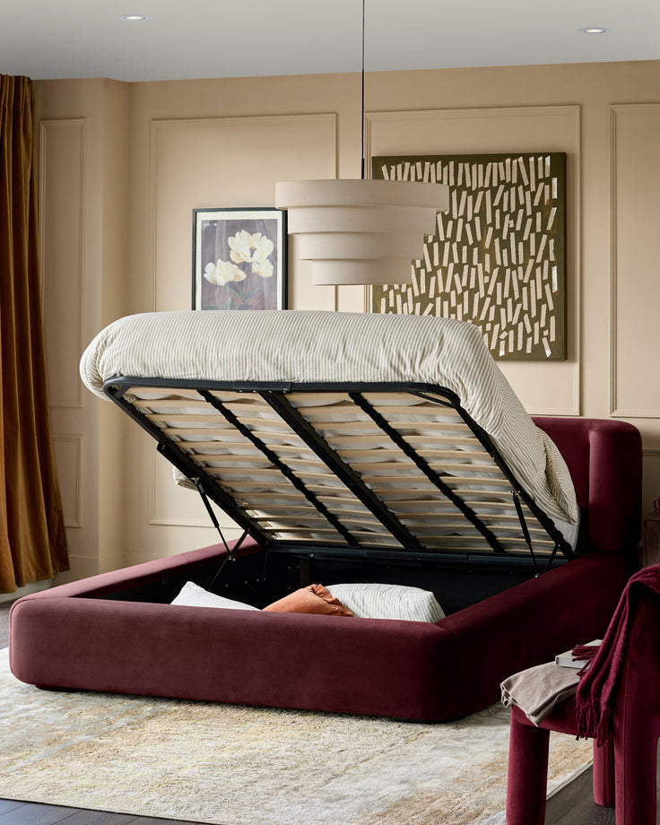 Darla King-Size Ottoman Bed in plum velvet with hydraulic lift mechanism open, showing striped bedding and wooden slat base.