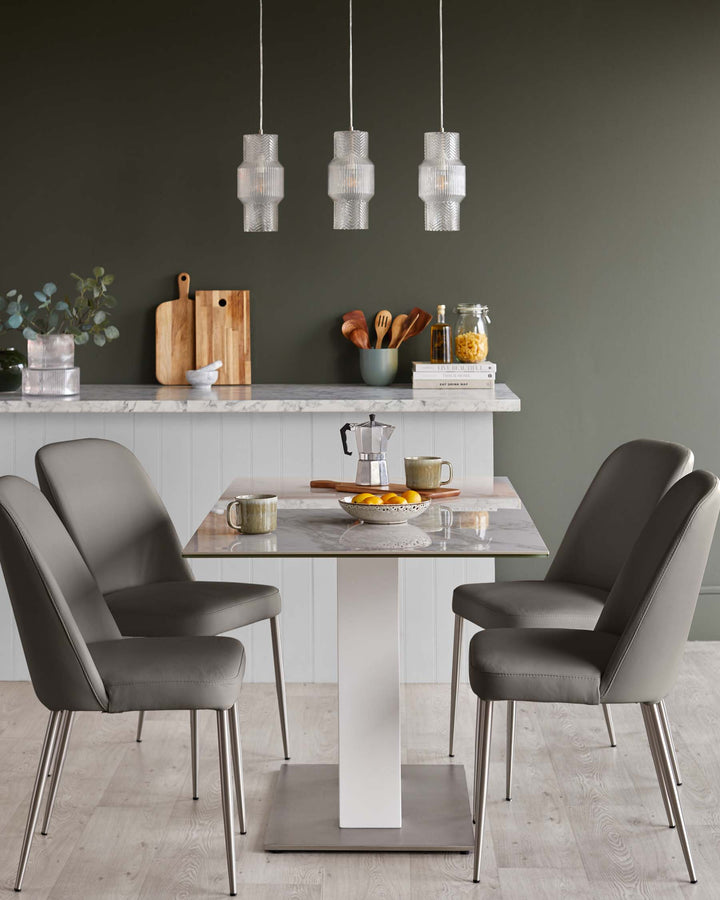 Dining area with grey upholstered chairs around a marble-look table, lit by three pendant lights.