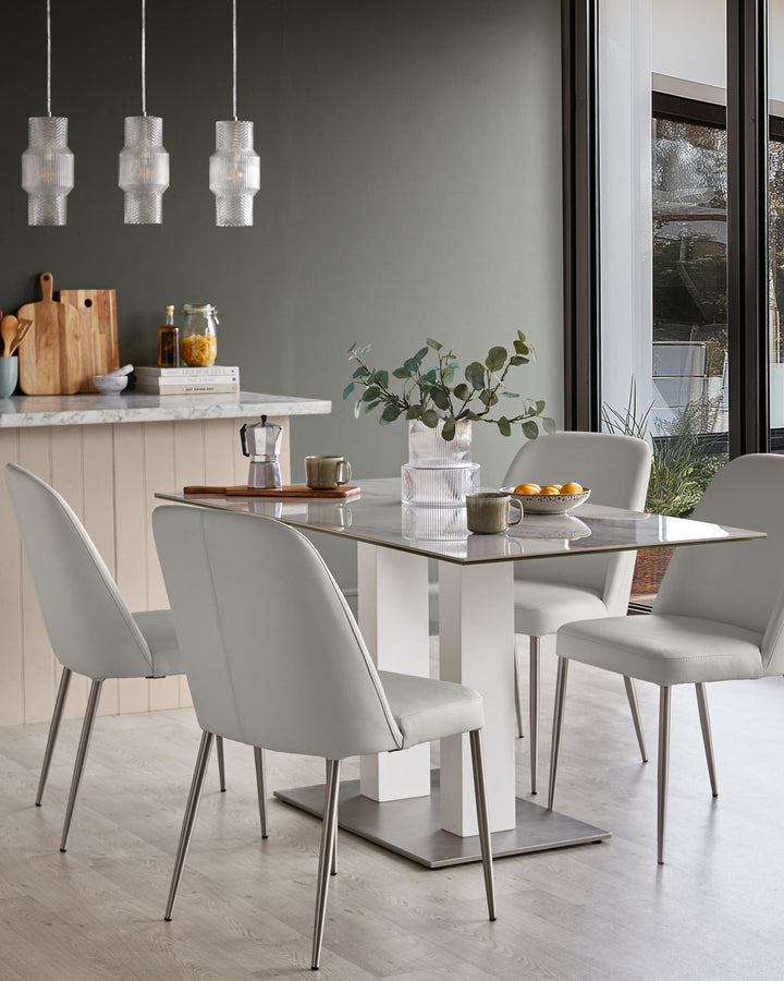 Contemporary dining set with a glass table, grey chairs and stylish pendant lights. Perfect for a modern dining space.