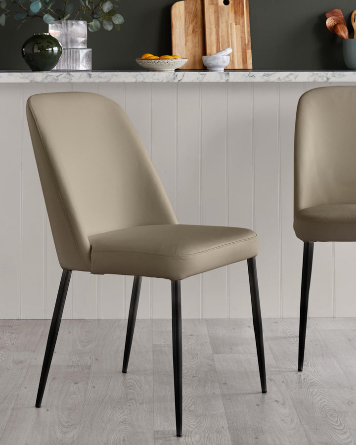 Two beige dining chairs with black metal legs, placed in a modern kitchen setting.
