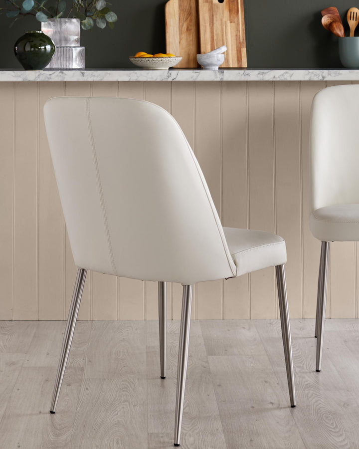 Pair of cream chairs with sleek metal legs. Stylish, contemporary design for modern dining or kitchen spaces.