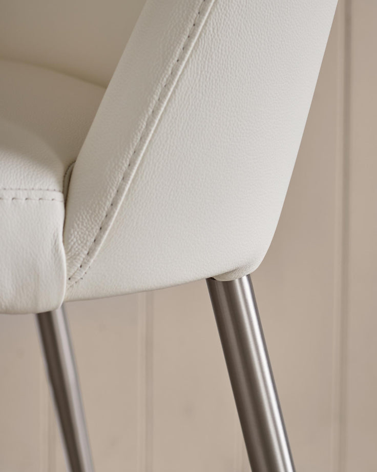 Close-up of a white leather chair with metal legs, showcasing its texture and modern design.