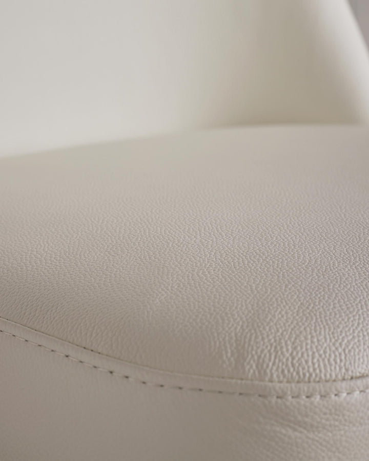 Close-up of a white leather chair seat with stitching detail, perfect for adding comfort to your home.
