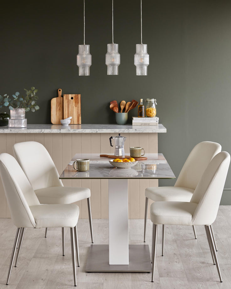 A modern dining set with marble table top, white chairs, and three hanging glass pendant lights.