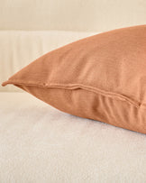 Rust-colored Delanie cushion in large size, displayed on a neutral surface showing its textured fabric and sewn seam detail.