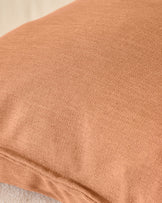 Close-up of rust-colored cushion fabric showing soft, textured weave detail.