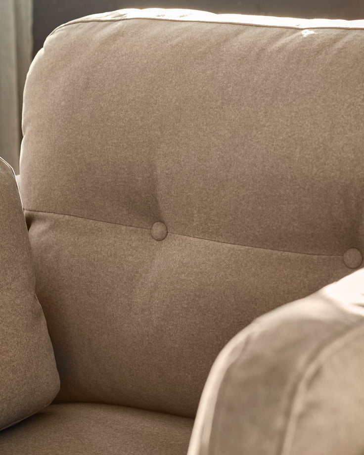 Delilah armchair in mocha fabric, showing close-up of buttoned backrest and curved wooden frame detail.