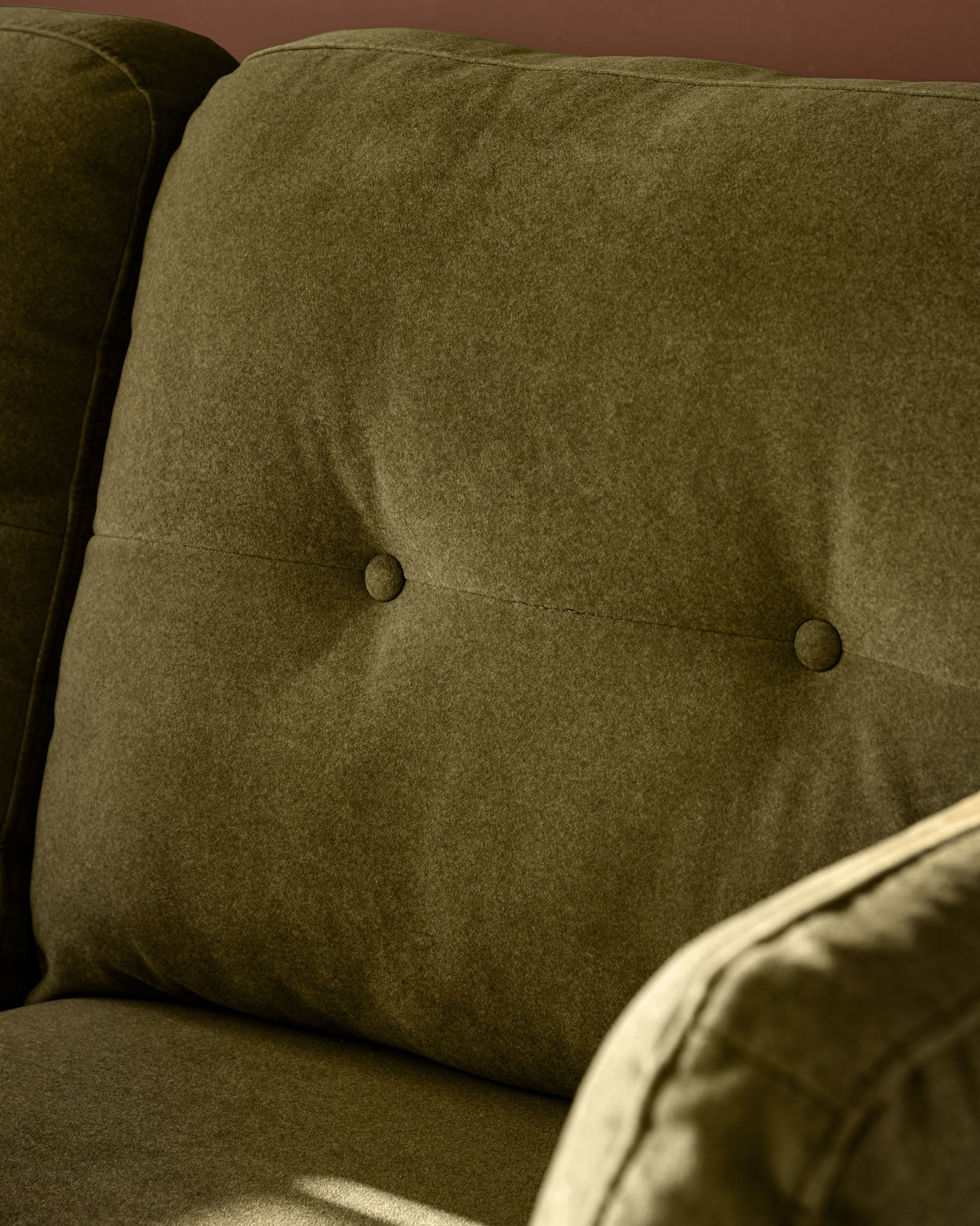 Pistachio green fabric 3-seater sofa with button-tufted backrest, angled detail view.