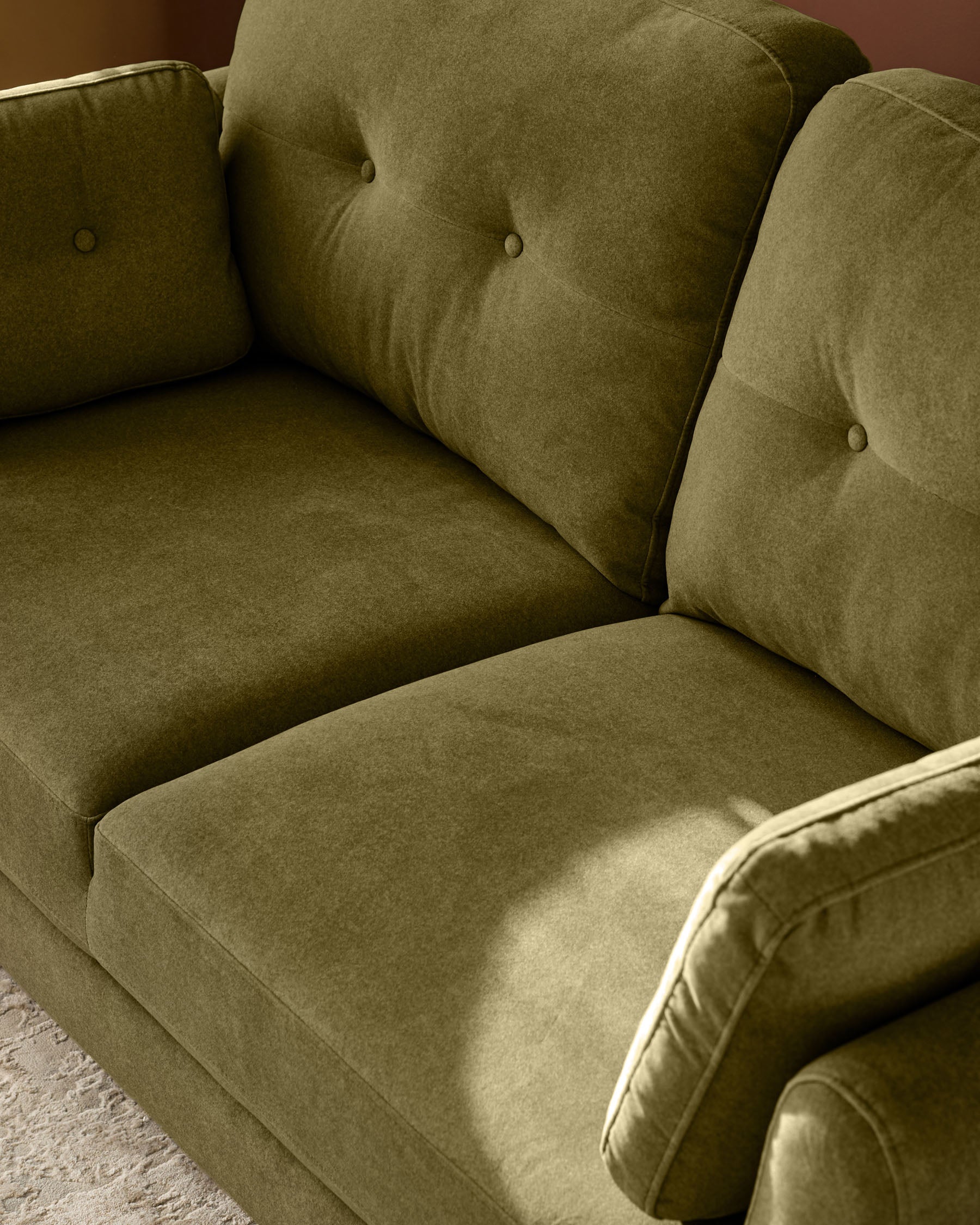 Delilah 3-seater sofa in pistachio green fabric, angled view showing button-tufted cushions and cream piping detail.