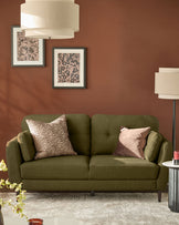 Pistachio green fabric sofa with rounded arms and tufted back, styled with decorative pillows in a rust-toned living room.