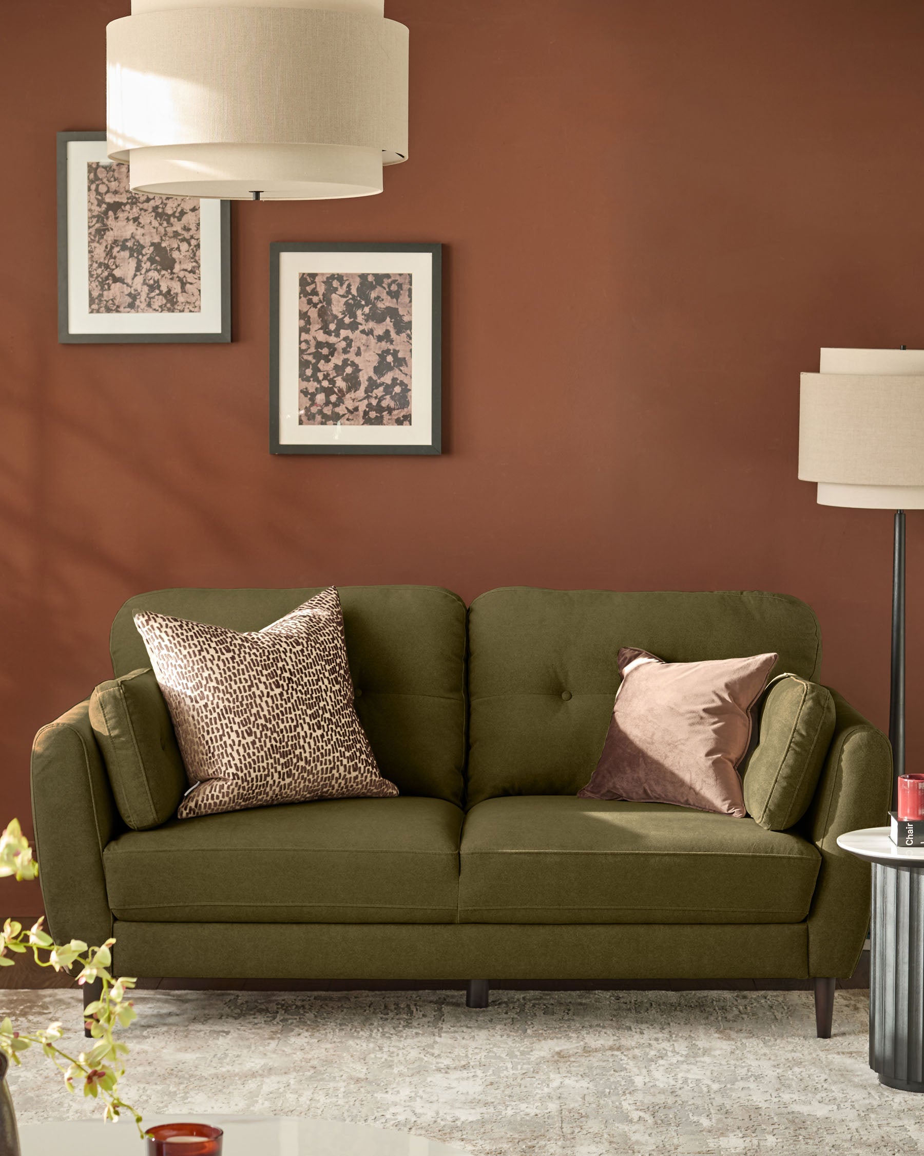 Pistachio green fabric sofa with rounded arms and tufted back, styled with decorative pillows in a rust-toned living room.