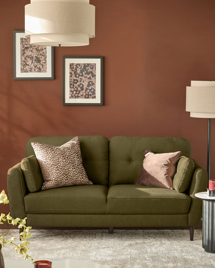 Pistachio green fabric sofa with rounded arms and tufted back, styled with decorative pillows in a rust-toned living room.