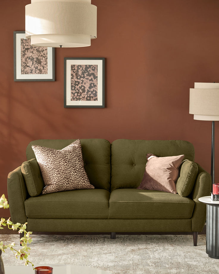 Pistachio green fabric sofa with rounded arms and tufted back, styled with decorative pillows in a rust-toned living room.