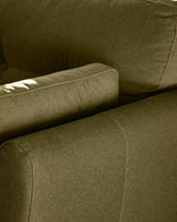 Pistachio green fabric armchair detail showing upholstered arm and seat cushion with stitched seams in natural daylight.