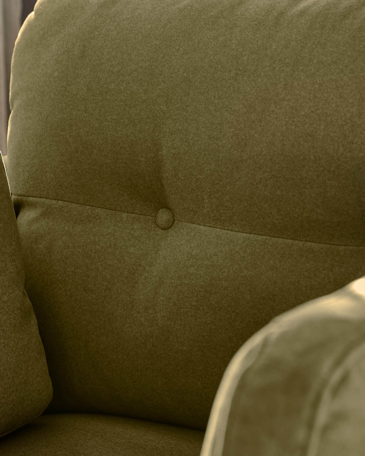 Delilah armchair in pistachio green fabric, showing close-up of seat back with button detail and curved armrest.