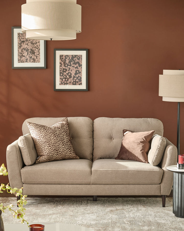 Delilah 3-seater sofa in mocha fabric with rounded arms, tufted back, and dark wooden legs, styled in a living room setting.