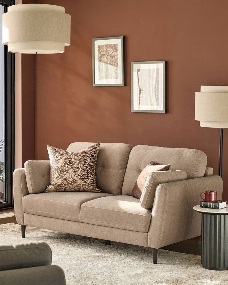 Delilah 3-seater sofa in mocha fabric, displayed in a styled living room setting with decorative pillows and warm terracotta walls.