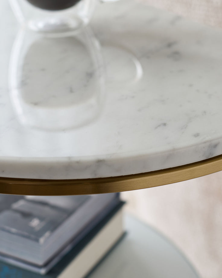 White marble demi-side table with brass trim detail, angled view showing round tabletop and metal base accent.