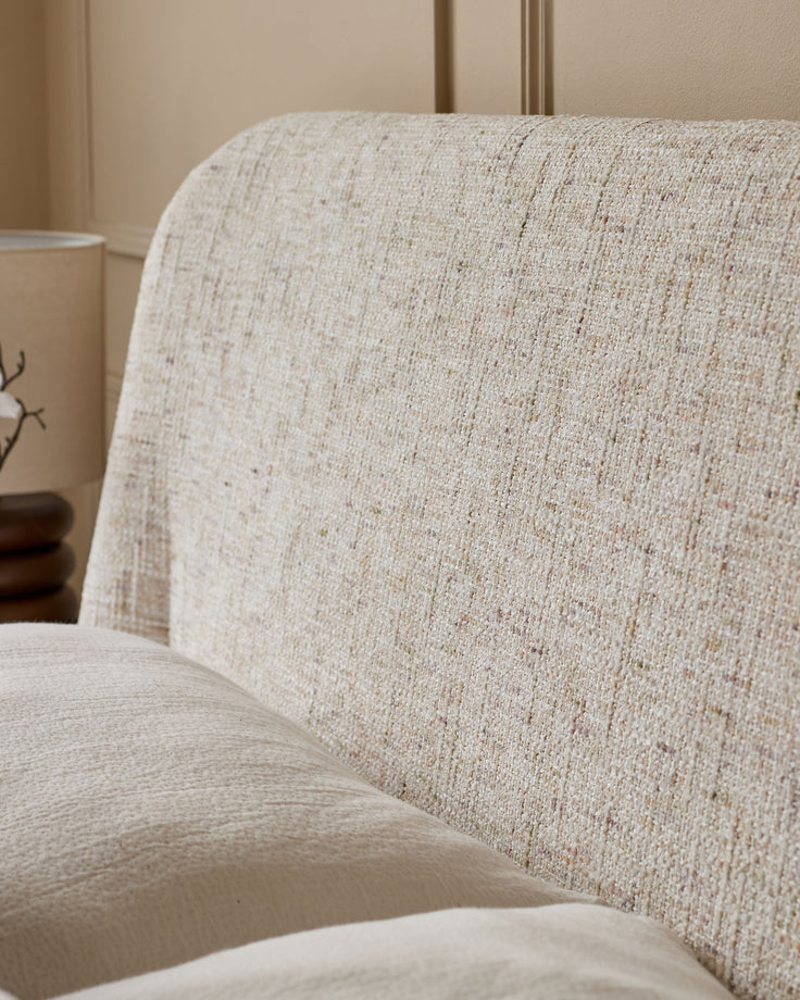 Cream upholstered ottoman bed with textured fabric, showing close-up of curved headboard and seat detail.