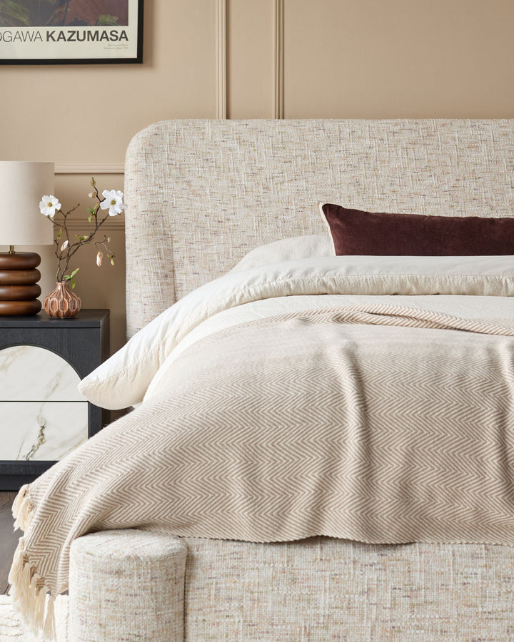 Deven king-size ottoman bed in natural linen fabric with rounded headboard, styled with bedding and bedroom accessories.