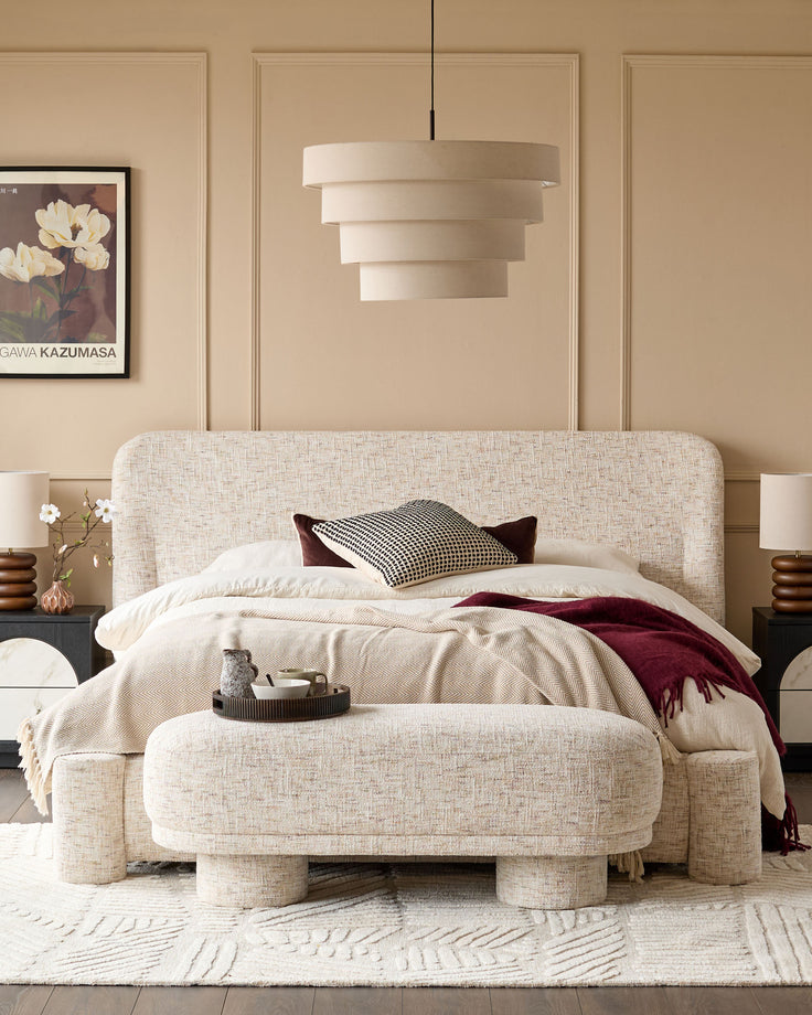Deven King-Size Ottoman Bed in natural fabric with rounded edges, displayed in a beige bedroom with matching bench.