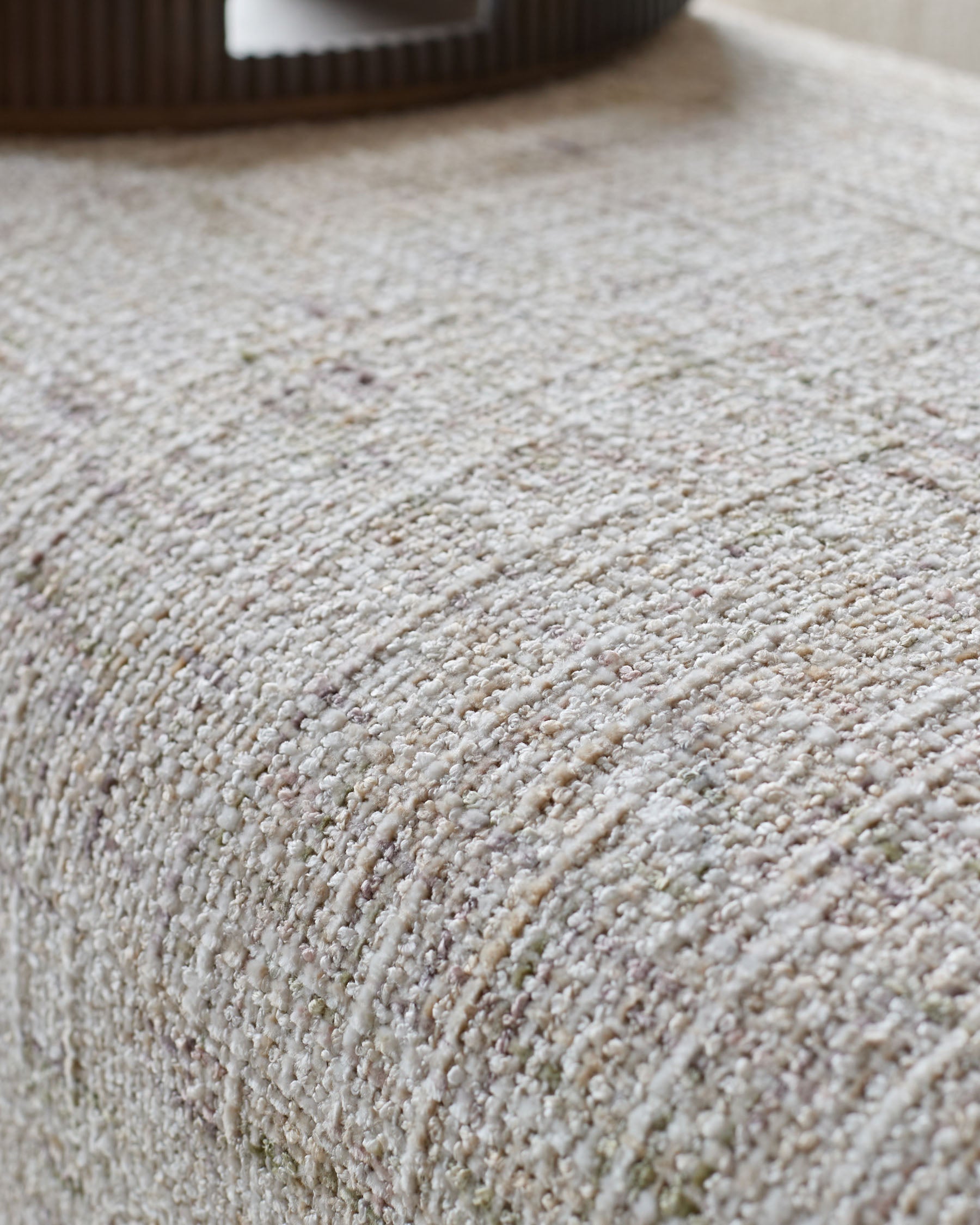 Close-up of natural beige textured fabric on Deven bench, showing woven surface detail.