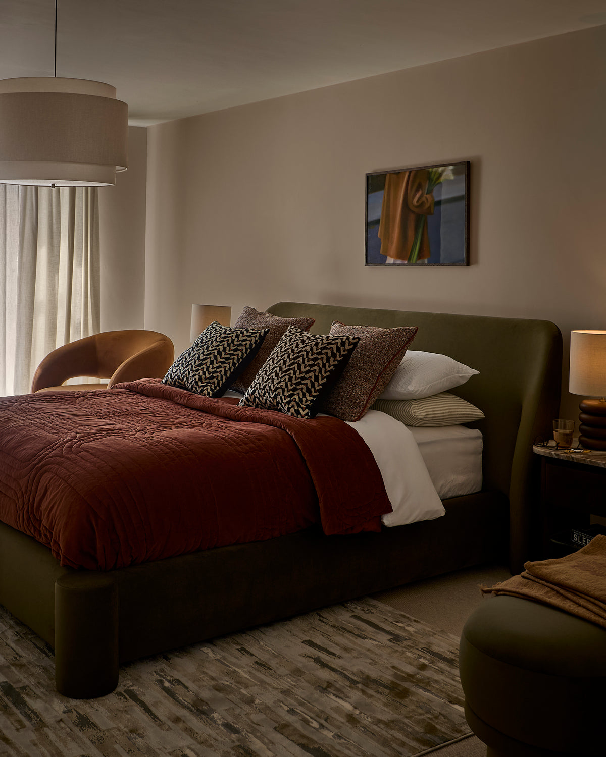 Deven king-size ottoman bed in olive-green velvet, styled in a modern bedroom with burgundy bedding and patterned cushions.