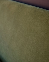 Close-up of Deven King-Size Ottoman Bed fabric in olive green velvet. Olive green velvet upholstery texture detail.