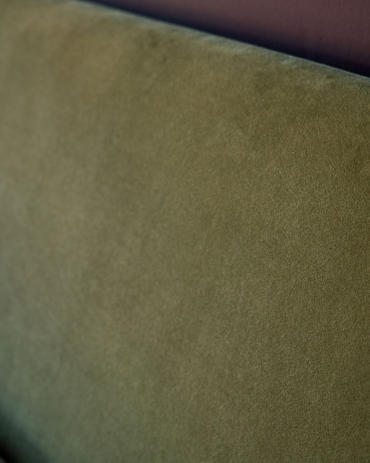 Close-up of Deven King-Size Ottoman Bed fabric in olive green velvet. Olive green velvet upholstery texture detail.