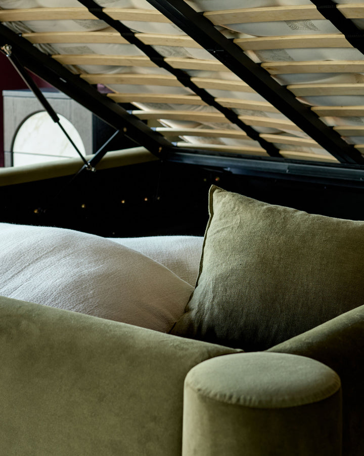 Deven king-size ottoman bed in olive-green velvet, shown open with storage visible and skylight overhead.