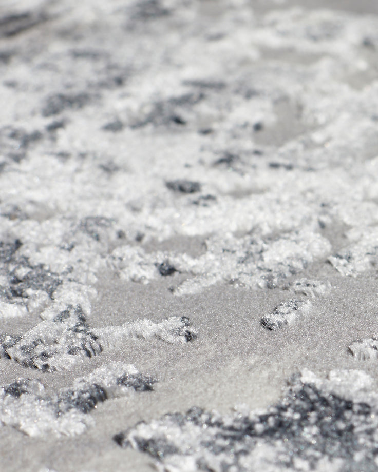 Close-up of grey distressed textured rug showing raised fibres and mottled surface pattern detail.