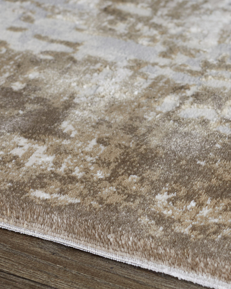 Close-up of distressed border textured rug in natural beige and cream tones showing pile detail and white binding edge.