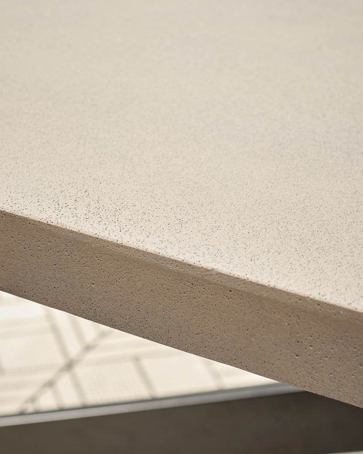 Close-up of concrete tabletop surface showing speckled light grey finish and edge detail with metal frame.
