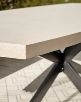 Concrete tabletop detail of Donato garden dining table, showing light grey surface and dark metal base frame.