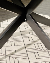 Dark grey dining table base with black metal X-frame legs on patterned carpet, angled view.