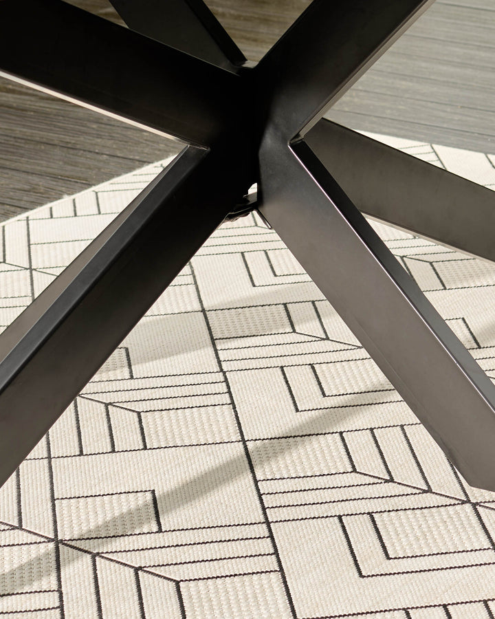 Dark grey dining table base with black metal X-frame legs on patterned carpet, angled view.