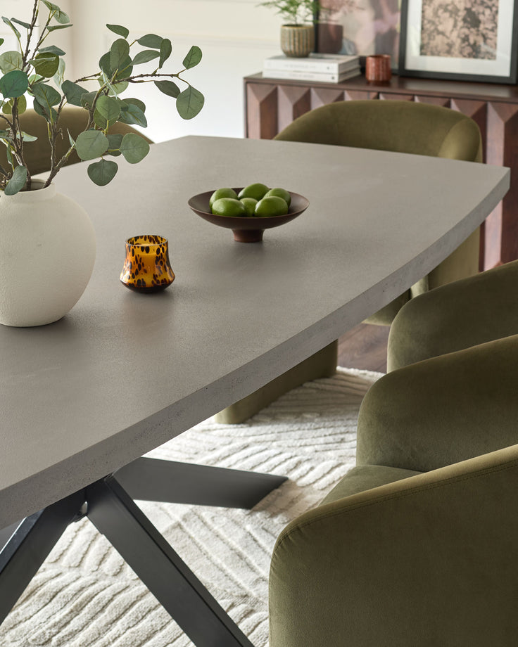 Donato dark grey dining table with light concrete top and black X-frame base, styled with green chairs and accessories.