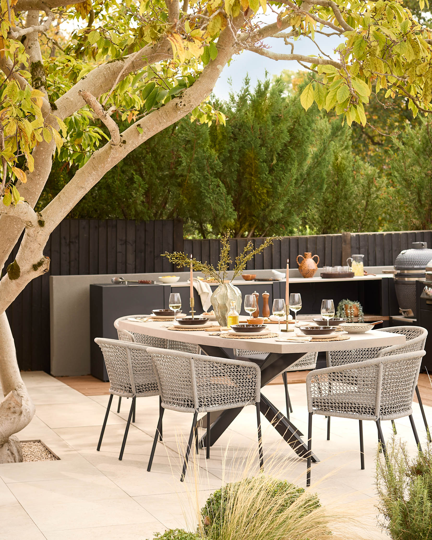 Donato dark grey 10-seater dining table styled in an outdoor patio setting with woven chairs and place settings.