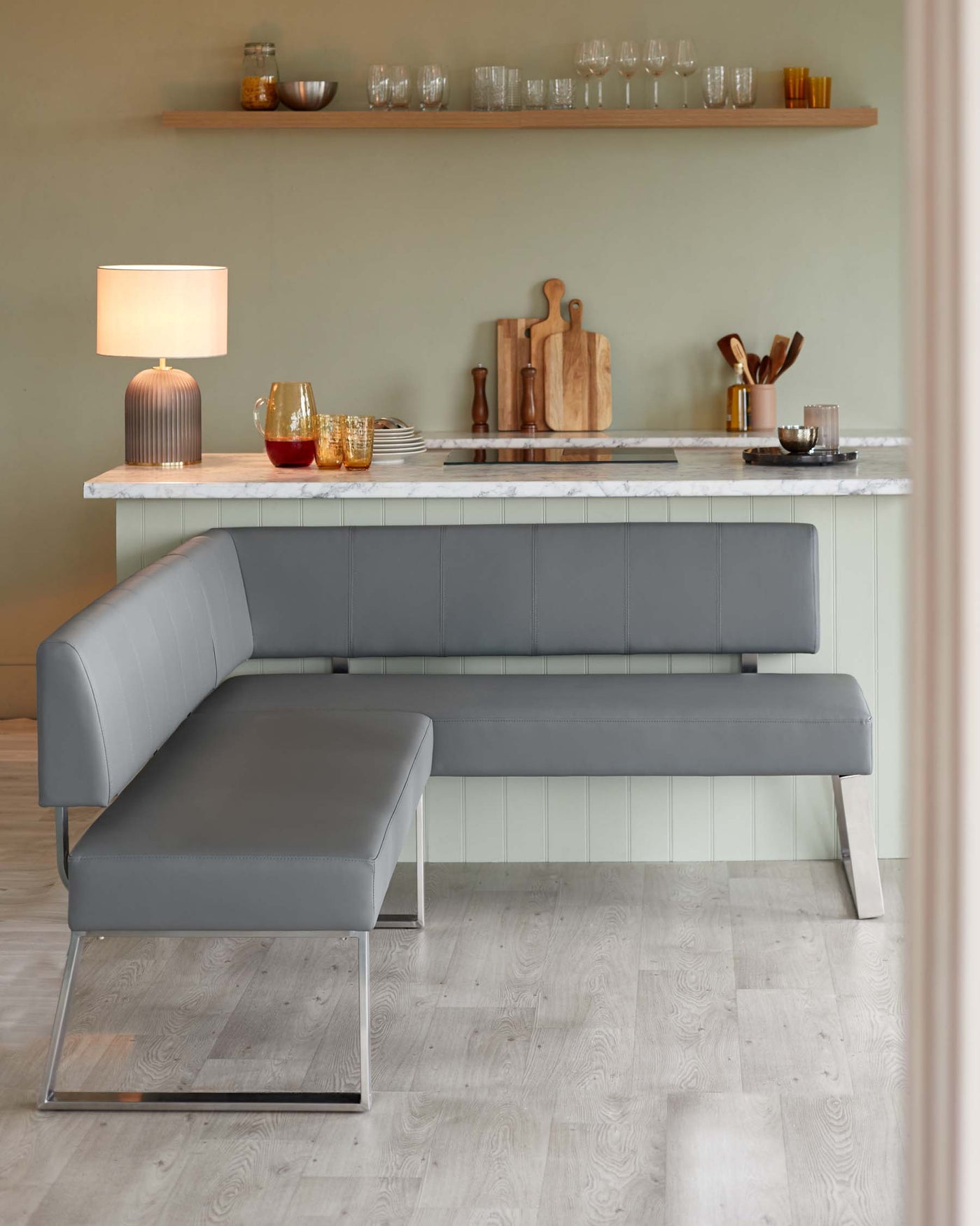 Modern minimalist kitchen seating furniture consisting of a sleek grey upholstered bench with clean lines and a matching single-seat ottoman, both featuring chrome metal bases.