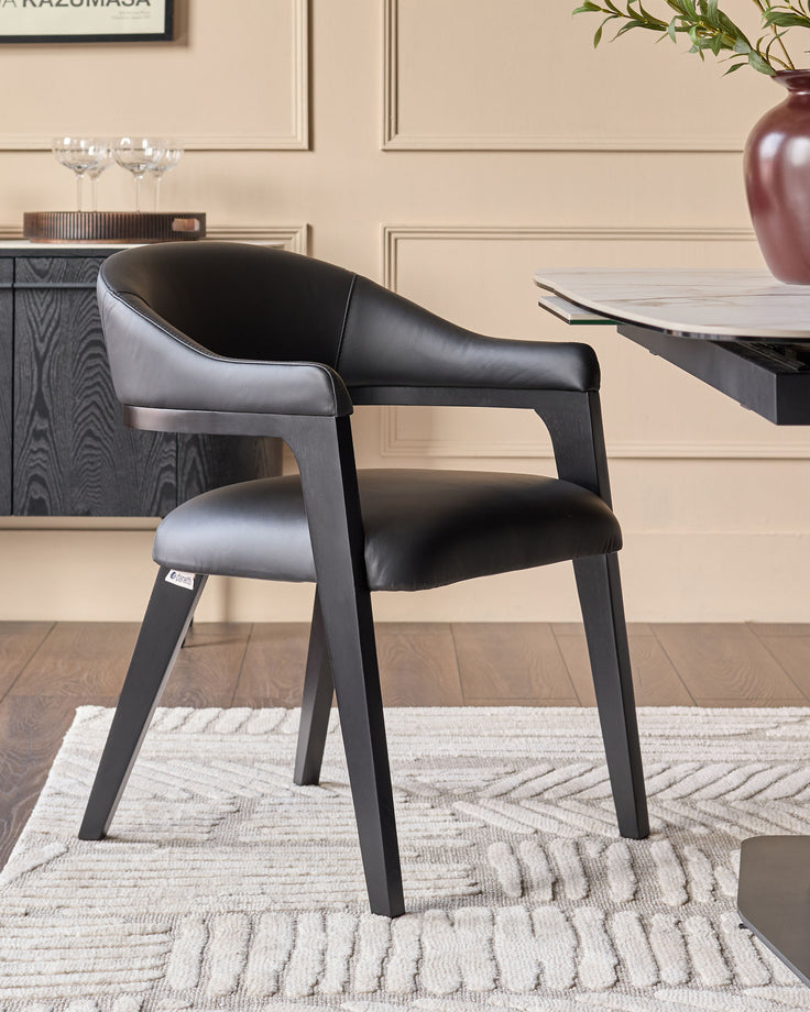 Dylan dining chair in black leather with dark wood frame, shown in modern dining room setting.