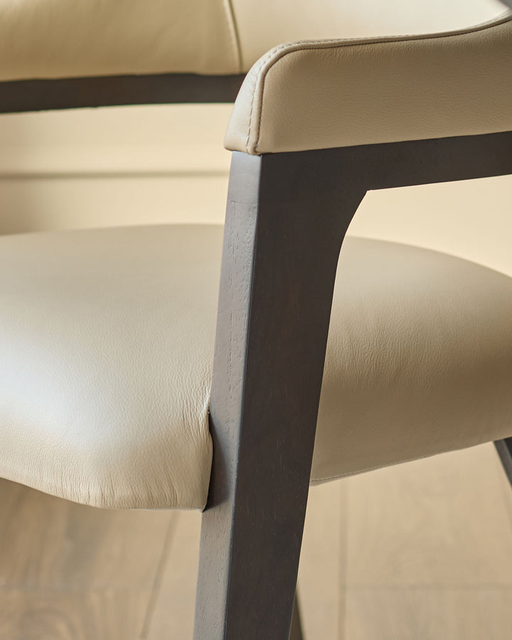 Dylan dining chair in natural leather, close-up of armrest and dark wood frame detail.