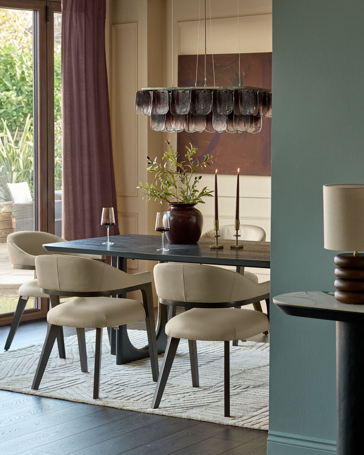 Dylan dining chair in natural leather, shown in a modern dining room setting with dark table and contemporary glass pendant light.