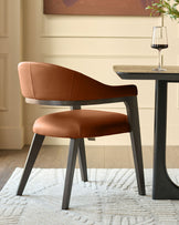 Dylan dining chair in tan leather with black wooden legs, shown at a table with a wine glass and plant.